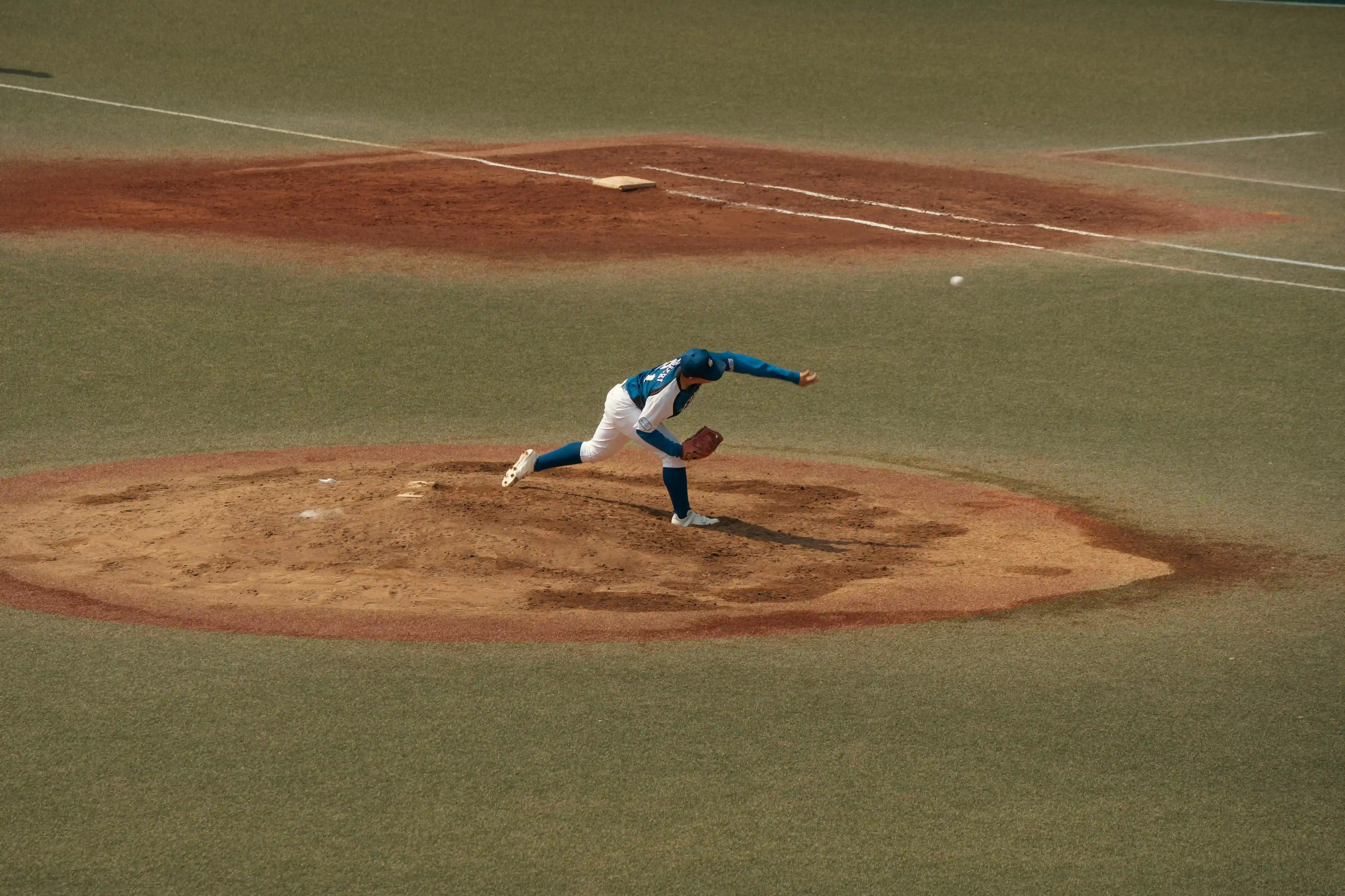 A skilled baseball pitcher delivers a pitch on a sunlit field in Tokyo, Japan. Captured in dynamic motion.