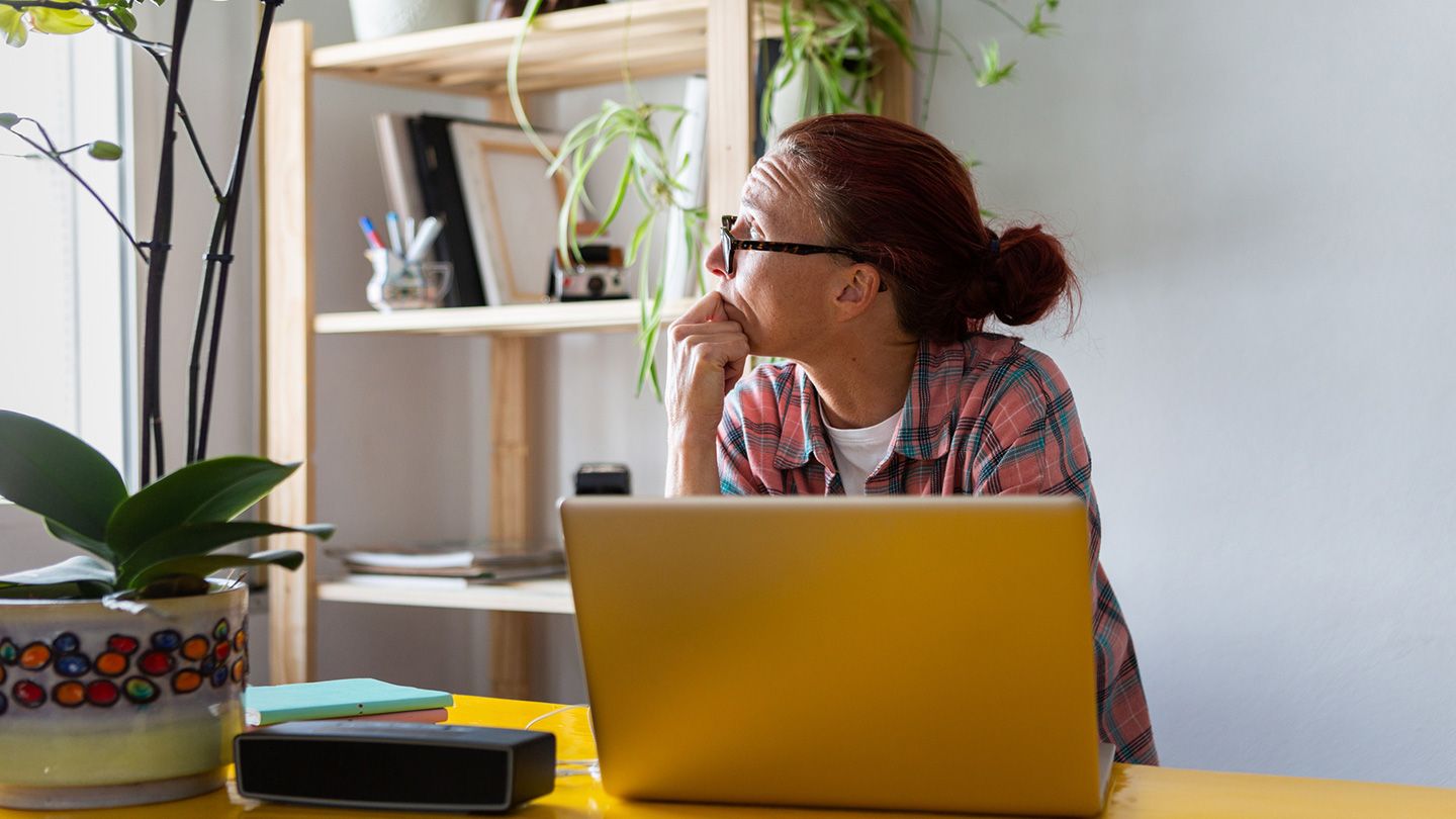 A women distractedly looks to her side with the laptop open in the front.