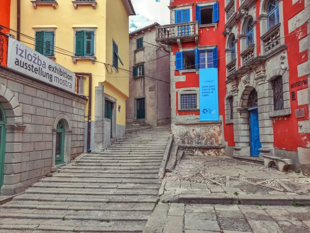 A narrow alley with steps leading up and buildings on both sides.
